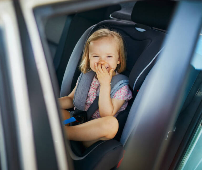 Smiling toddler safely seated in a forward-facing car seat inside a chauffeured vehicle in Chicago