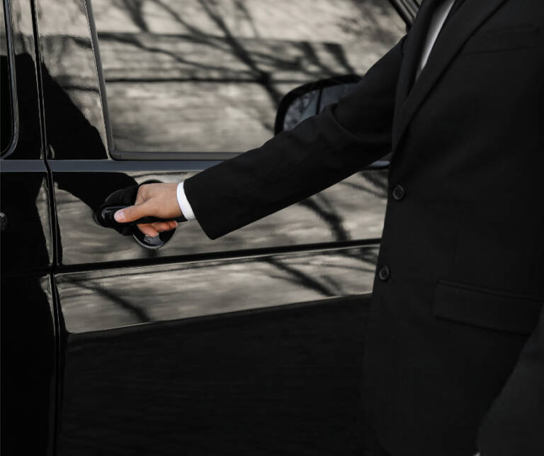 Chauffeur in black suit opening the door of a luxury black SUV for a client in Chicago