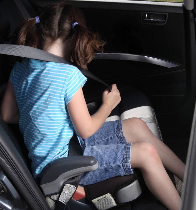 Young girl in booster seat buckled up inside a professional limo in Chicago for safe toddler transportation